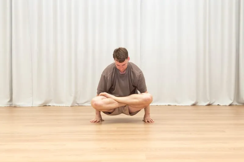Keegan sitting in a full lotus with his legs crossed and folded in, both palms planted on the floor either side of his hips