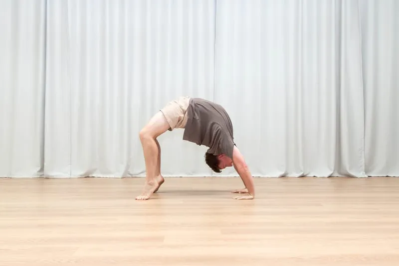 Keegan in a bridge, hands and feet on the floor with his hips lifted and his chest and shoulders open