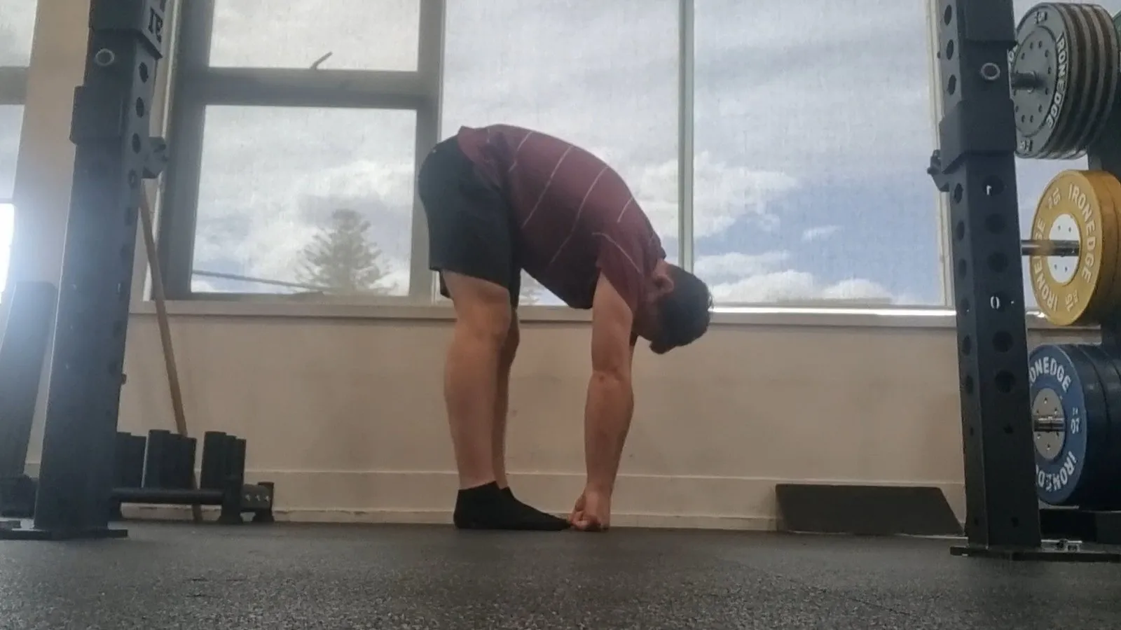 Keegan in a standing forward fold with straight legs, reaching down to touch his toes